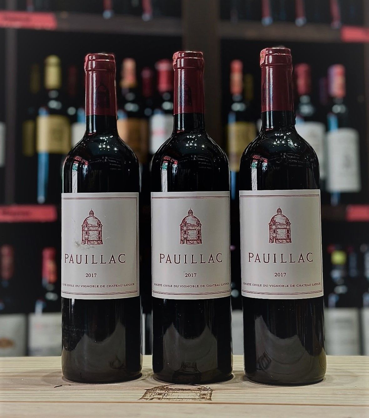 三支直立在木面上的酒瓶,正標印有 PAUILLAC 和 2017,紋章是圓頂建築,並有 SOCIETE CIVILE DU VIGNOBLE DE CHATEAU LATOUR