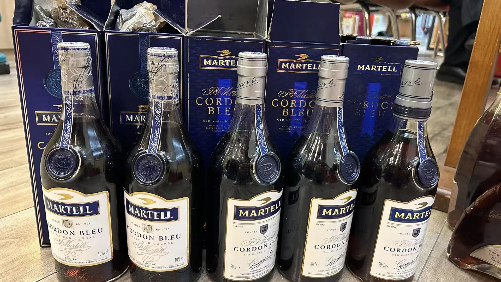 五瓶 Martell Cordon Bleu 與深藍色酒盒並排，酒標可見 Extra Old Cognac 和 Old Classic Cognac 不同字樣