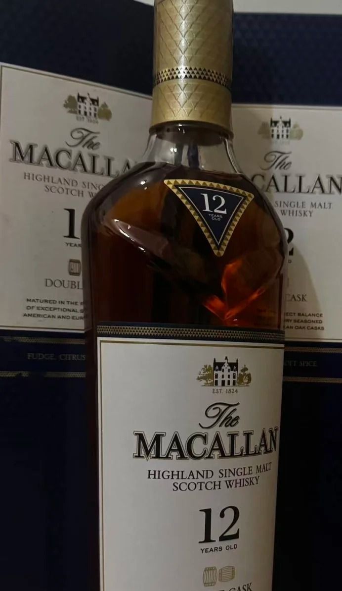 深色背景前一只麥卡倫 12 年雙桶玻璃瓶，金色封膜完整，正標寫 MACALLAN 與 DOUBLE CASK，瓶頸可見酒液，畫面沒有外盒