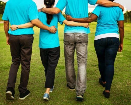 Stock four people walking arm in arm in matching blue t-shirts