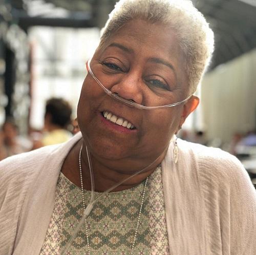 Older woman with short gray hair smiling while wearing a nasal cannula