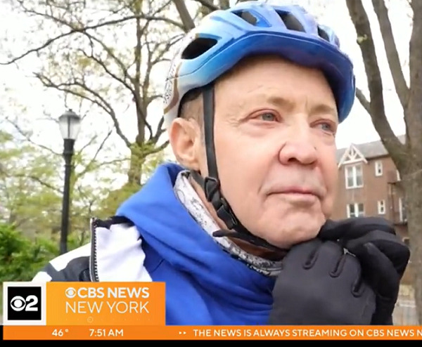 Jerry Cahill adjusts his blue bike helmet outdoors with black-gloved hands. He has light skin, gray hair, and light eyes.