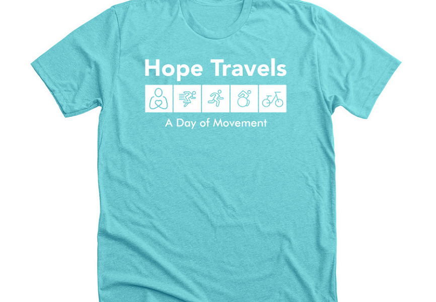 A Bonfire t-shirt in light blue is slightly wrinkled to show its texture with the Hope Travels: A Day of Movement logo printed across the chest in white.