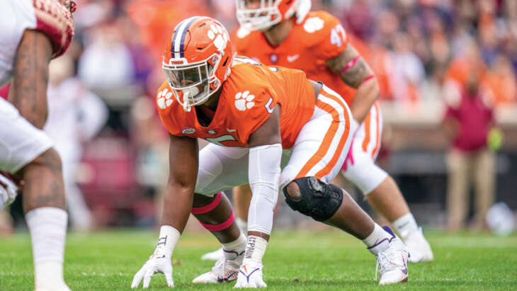 Clemson's KJ Henry wears his bright orange football uniform. He has brown skin.