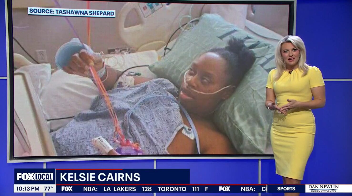 Heart transplant candidate Tashawna Shepard is interviewed by FOX Orlando. The headline reads FOX 35 Kelsie Cairns, which is the name of the reporter. Kelsie is standing in front of a large screen displaying a photo of Tashawna. Kelsie has light skin, shoulder-length blonde hair, and a lemon-yellow formal dress. In the photo behind her, lying in a hospital bed in a hospital gown,with tubes connected to her nose and arms, Tashawna has brown skin, brown eyes, and black hair pulled up into a bun.