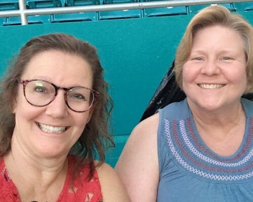 Two smiling women posing for a selfie in stadium seats
