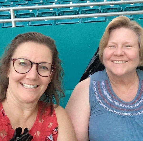 Two smiling women posing for a selfie in stadium seats