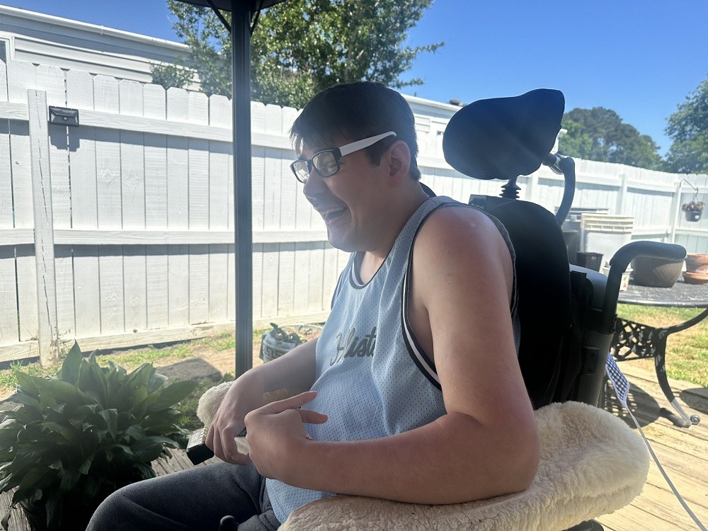 41-year-old Gerald Avant seated in his black power chair smiling on an outdoor deck.