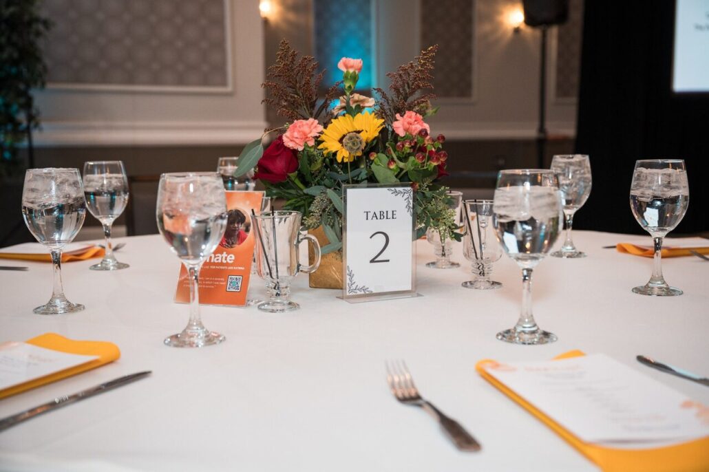 Table settings with white tablecloth and gold napkins at the 2024 Live It Up! gala supporting Help Hope Live.