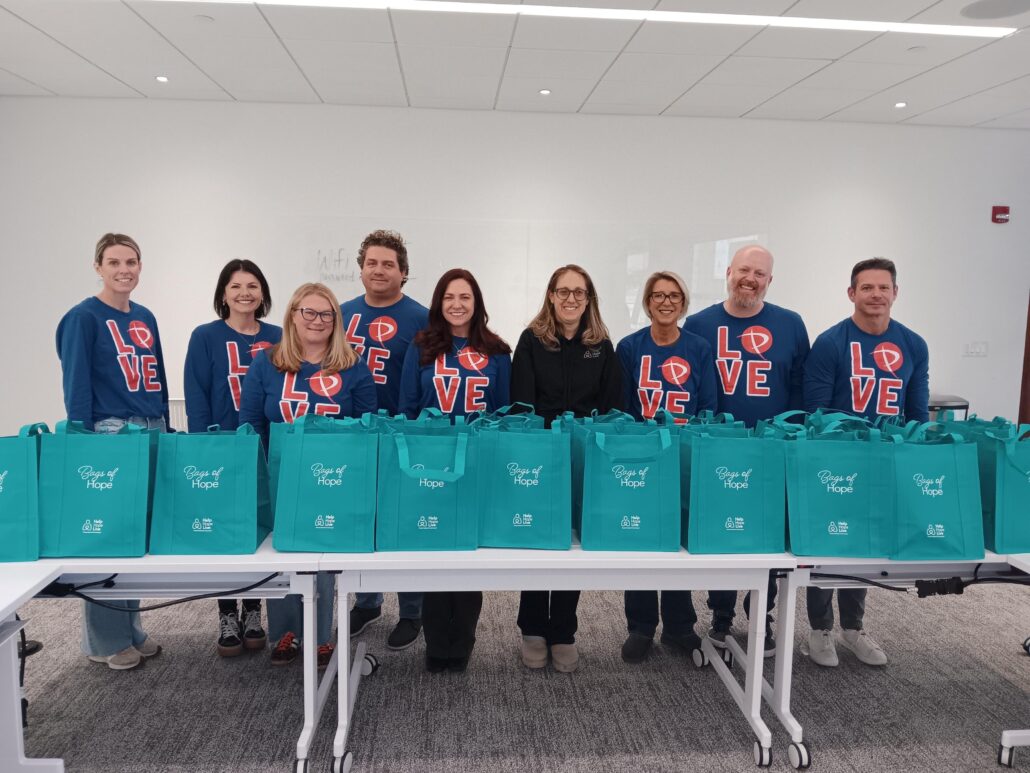 Prelude Solutions team with packed Bags of Hope and matching Love shirts in December 2025 with Brooke from Help Hope Live.