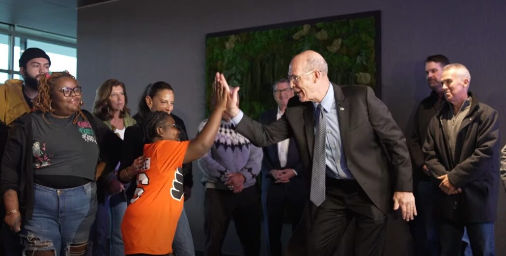 Raymeer Bacon-El high fives Brad Marsh of the Flyers Alumni at an Oct 2025 adaptive bike giveaway.