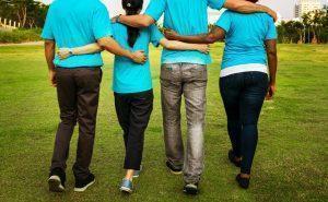 Stock four people walking arm in arm in matching blue t-shirts