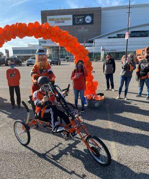Jackson Epstein receiving adaptive bike with Philadelphia Flyers Alumni and Gritty