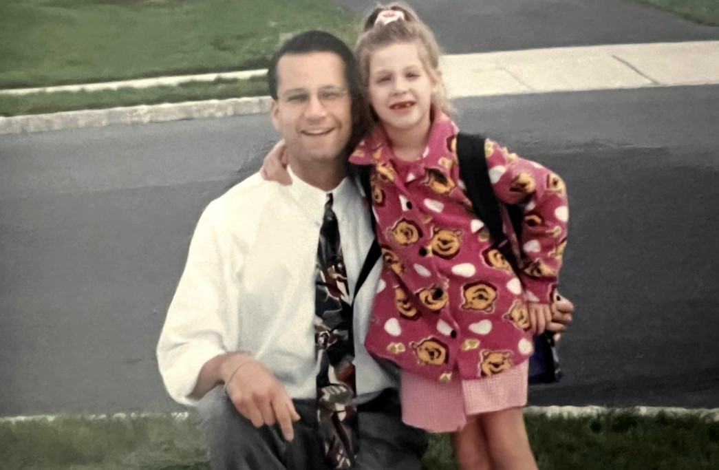 Heart transplant recipient Bill Soloway as a younger man with his young daughter, who has missing teeth, a high ponytail, and a brightly-printed shirt. She wears a backpack. Bill wears a suit and tie.