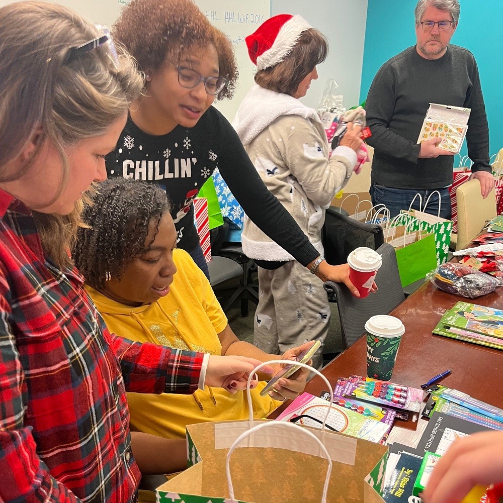 Several Help Hope Live team members pack Bags of Hope in the Help Hope Live offices, wearing festive pajamas.