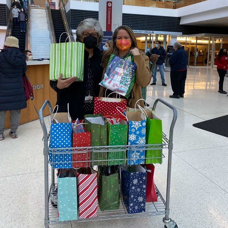 Help Hope Live's Sonny Mullen and transplant professional Deb Gordon are in the lobby of the Hospital of the University of Pennsylvania (HUP) holding Bags of Hope with a cart full of additional colorful bags in front of them, ready for delivery.