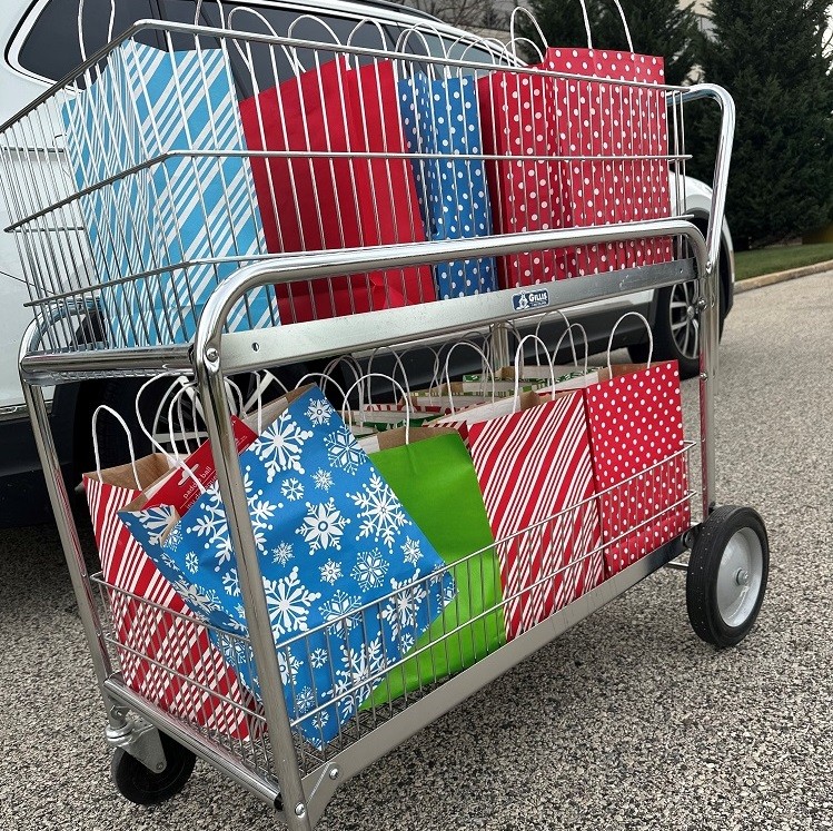 Colorful Bags of Hope bags are on a two-level rolling silver cart, ready for delivery.