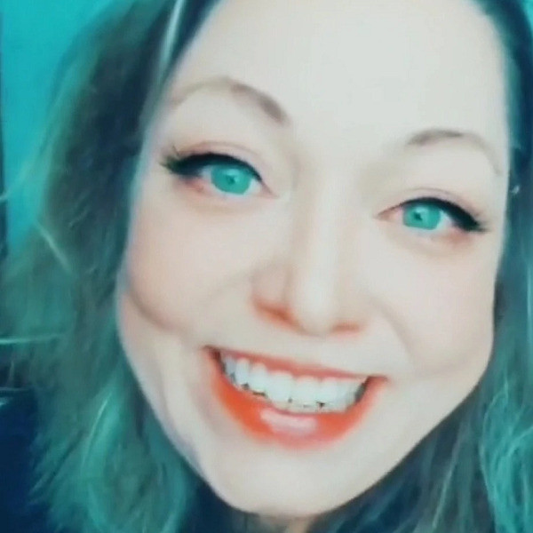 In a modified photo, liver transplant recipient Pryncyss Grey has light skin, bright blue eyes with winged eyeliner, light skin, a big smile, and shoulder-length hair that appears blue-green.