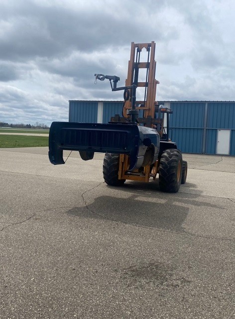 A forklift outdoors lifts a portion of an accessible vehicle frame for repairs.