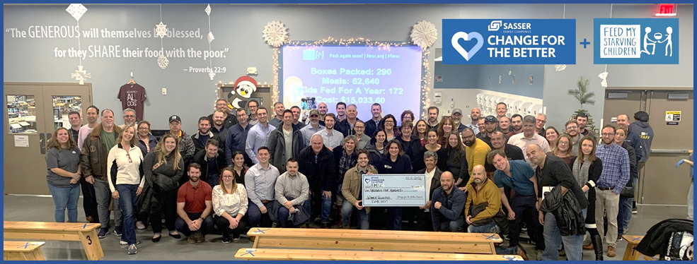 Two dozen members of the Express 4x4 team wear corporate workplace clothing as they hold a check to the charity Feed My Starving Children.