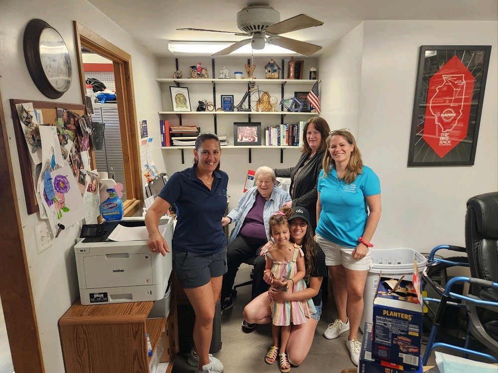Kelly L Green and Sonny Mullen are inside the office section of The Bike Rack in Chicago with co-founders Tammy and Katherine and Katherine's young daughter. With them is a seated woman older than Tammy and Katherine with gray hair.