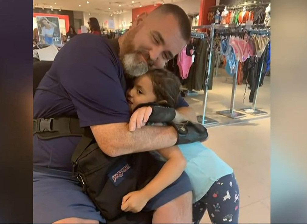 David Woodson is in a store hugging a young girl. He is seated in his wheelchair and has light skin and a salt-and-pepper beard.