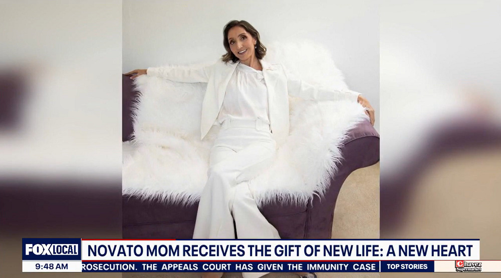 A photo of Manoela Vieira prior to her heart transplant shows her in a white suit on a white faux-fur throw over a purple couch. She has shoulder-length curly brown hair, light brown skin, and red lipstick with heavy eye makeup. The ticker along the bottom of the screen reads FOX Local 9:45 am: Novato Mom Receives the Gift of New Life: A New Heart.