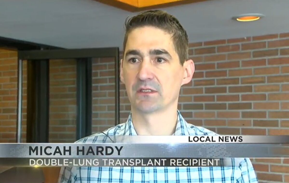 Transplant candidate Micah Hardy is on a news broadcast with the headline DOUBLE-LUNG TRANSPLANT RECIPIENT. He has light skin, dark eyes, and short gray hair.