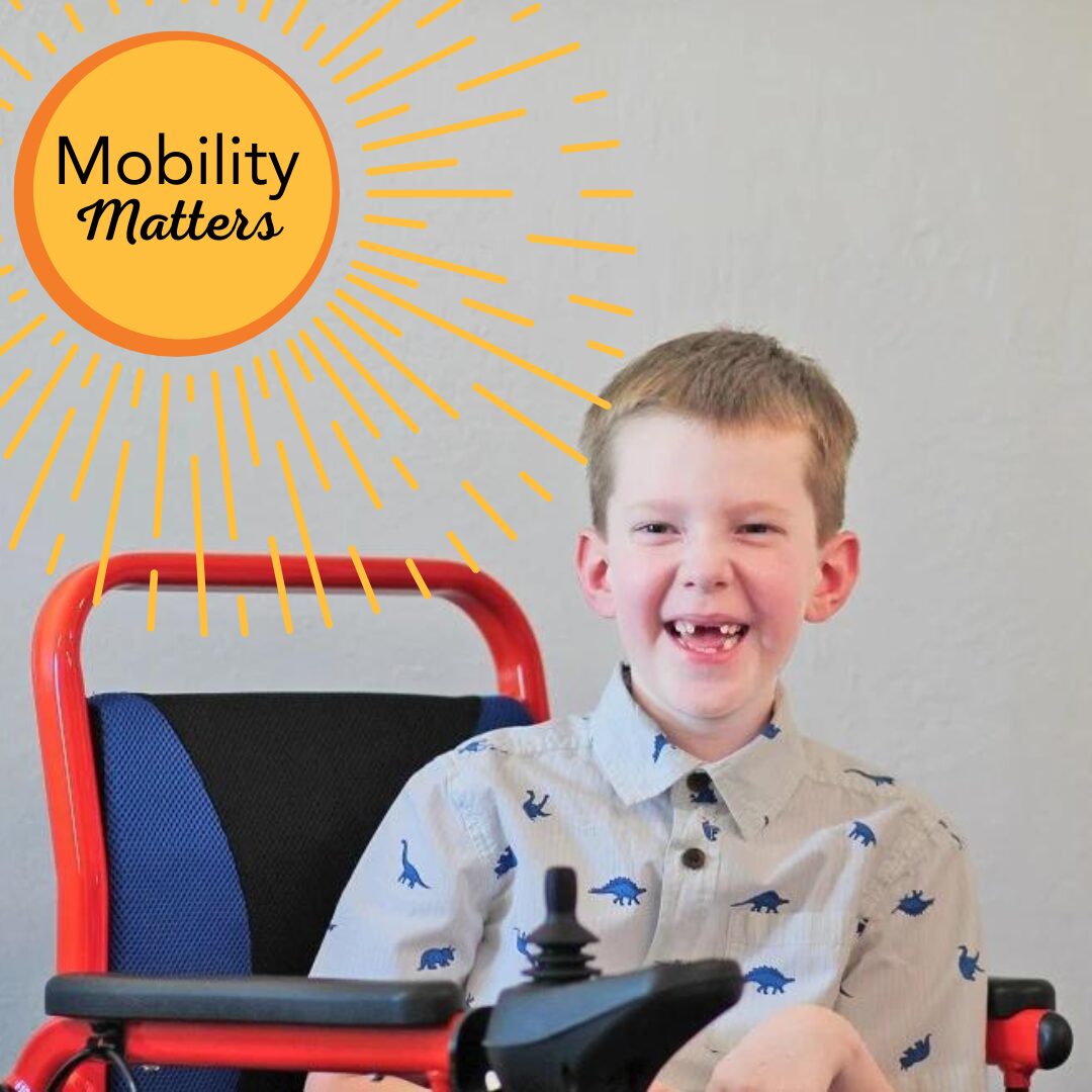 Carson Tussing is seated in a red and blue electric mobility device. He has light skin, his two front teeth missing, and short light brown hair and he wears a collared short-sleeved shirt with dinosaurs printed on it. A sunburst graphic in yellow and orange at the top left reads Mobility Matters.