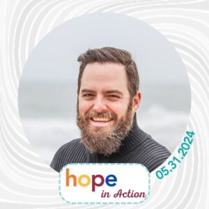 A client social media frame example for Hope in Action features the Hope in Action logo in orange, yellow, red, and blue text and the date 05.31.2024. The background is a gray wind-like swirl. The example client photo is a man with light skin, short brown hair, a brown and gray beard, a smile, and a gray turtleneck.