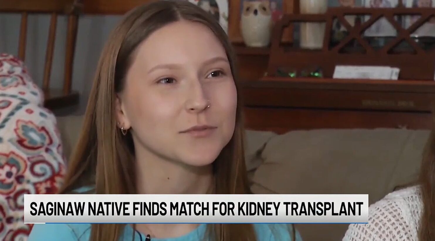 A screenshot from a TV interview with 23-year-old Rylee Wobio with a ticker that reads Saginaw Native Finds Match for Kidney Transplant. Rylee has light skin, straight brown hair, and brown eyes. She has a silver nosering on the left side of her nose.