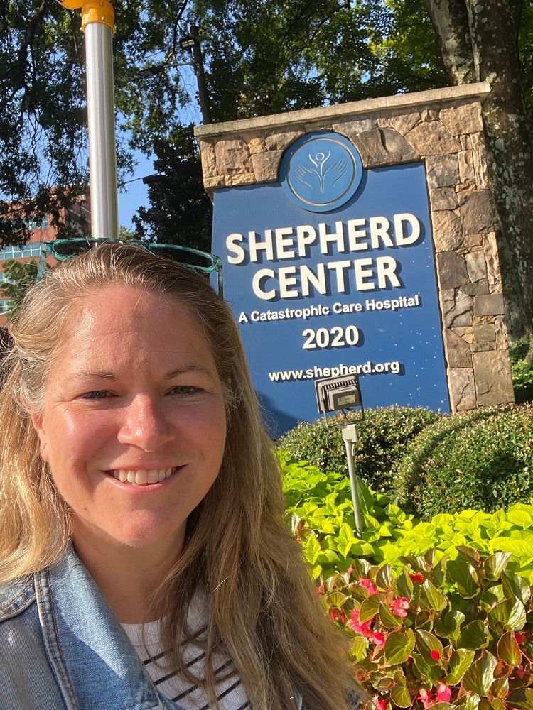 Sonny from Help Hope Live with the Shepherd Center facility sign in Atlanta.