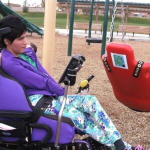 44-year-old Toña Rivera seated in her purple power chair with adaptive communication devices. She has light brown skin and short black hair.