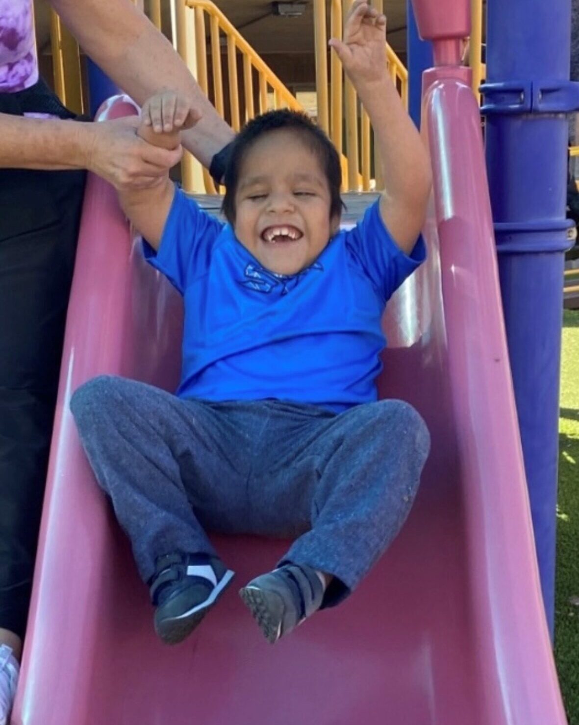 Favio being assisted down a slide.