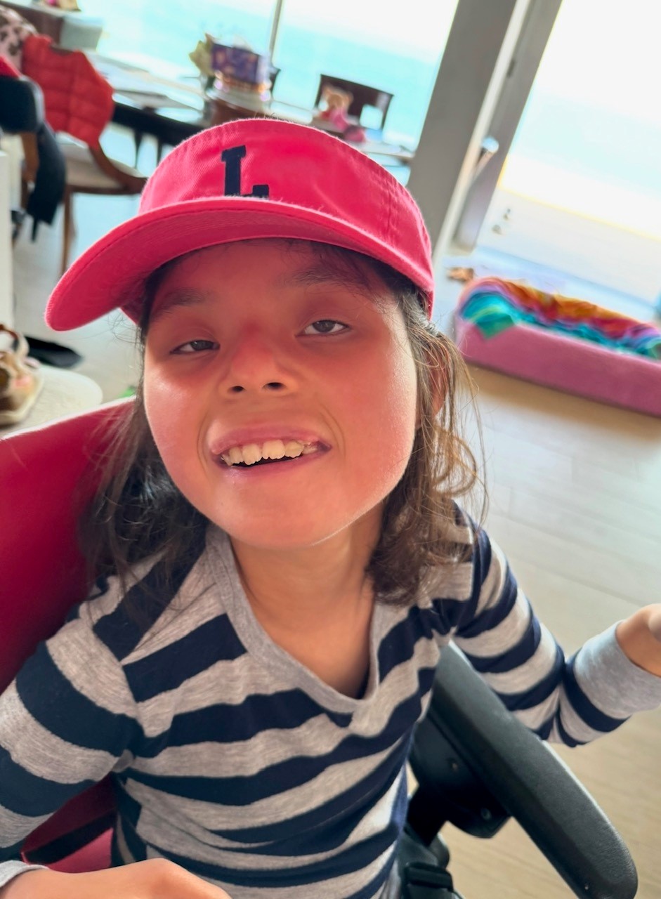 Pippi is sitting, wearing a pink hat, and smiling.