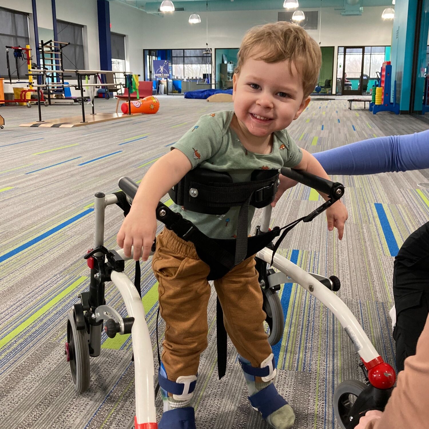 3-year-old Sidney Schmid stands in a walker device in physical therapy.