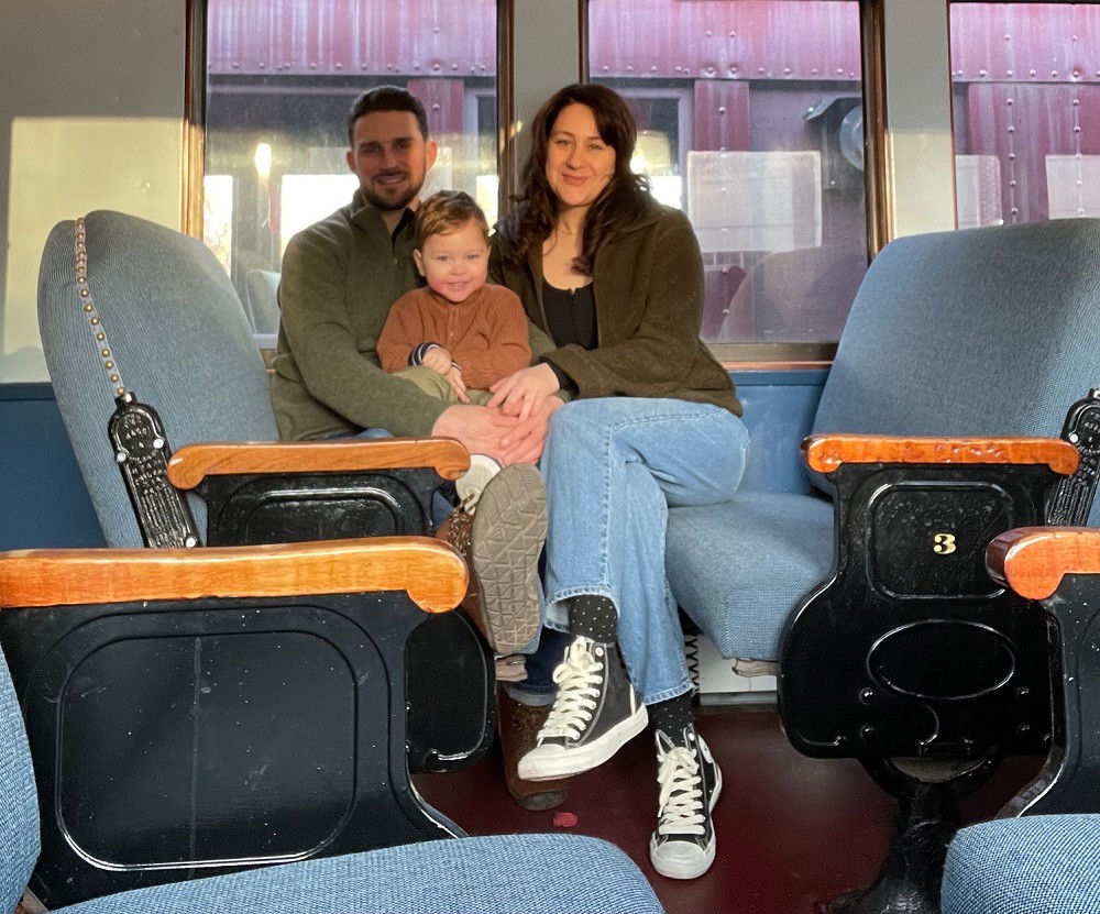 3-year-old Sidney Schmid sits between his mom and dad on a train.