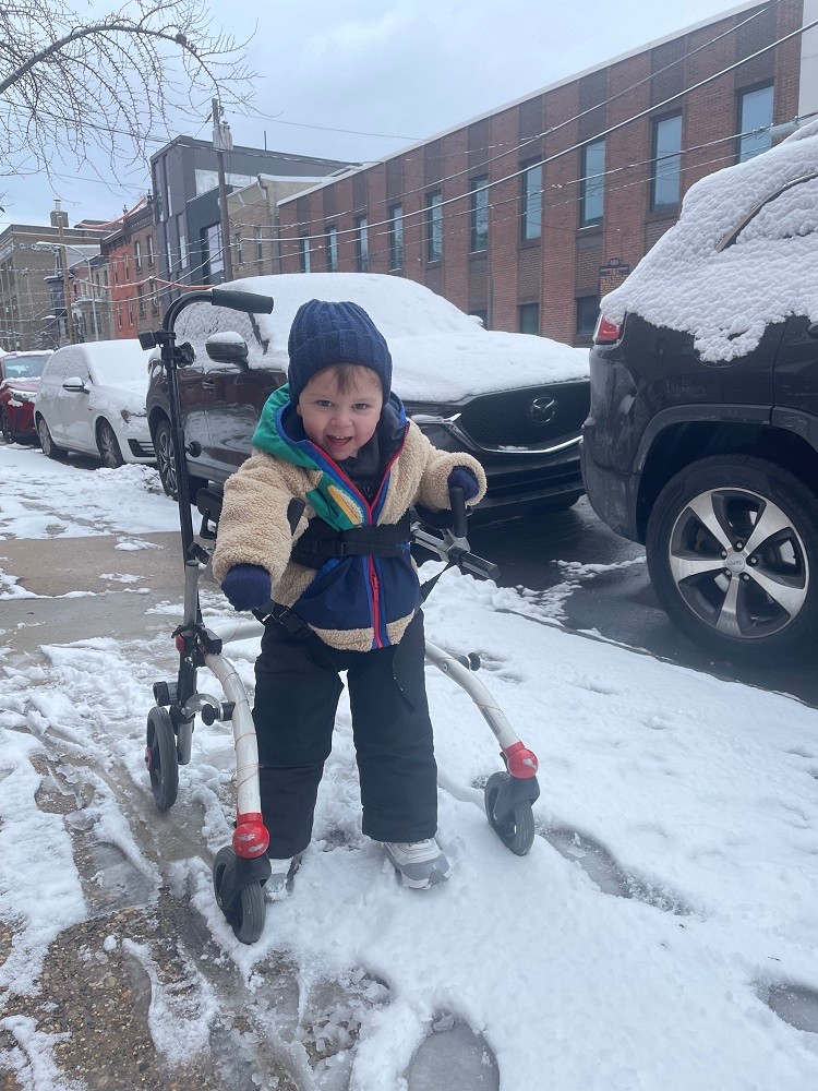 3-year-old Sidney Schmid rolls through the snow in a mobility device on the streets of Philadelphia.