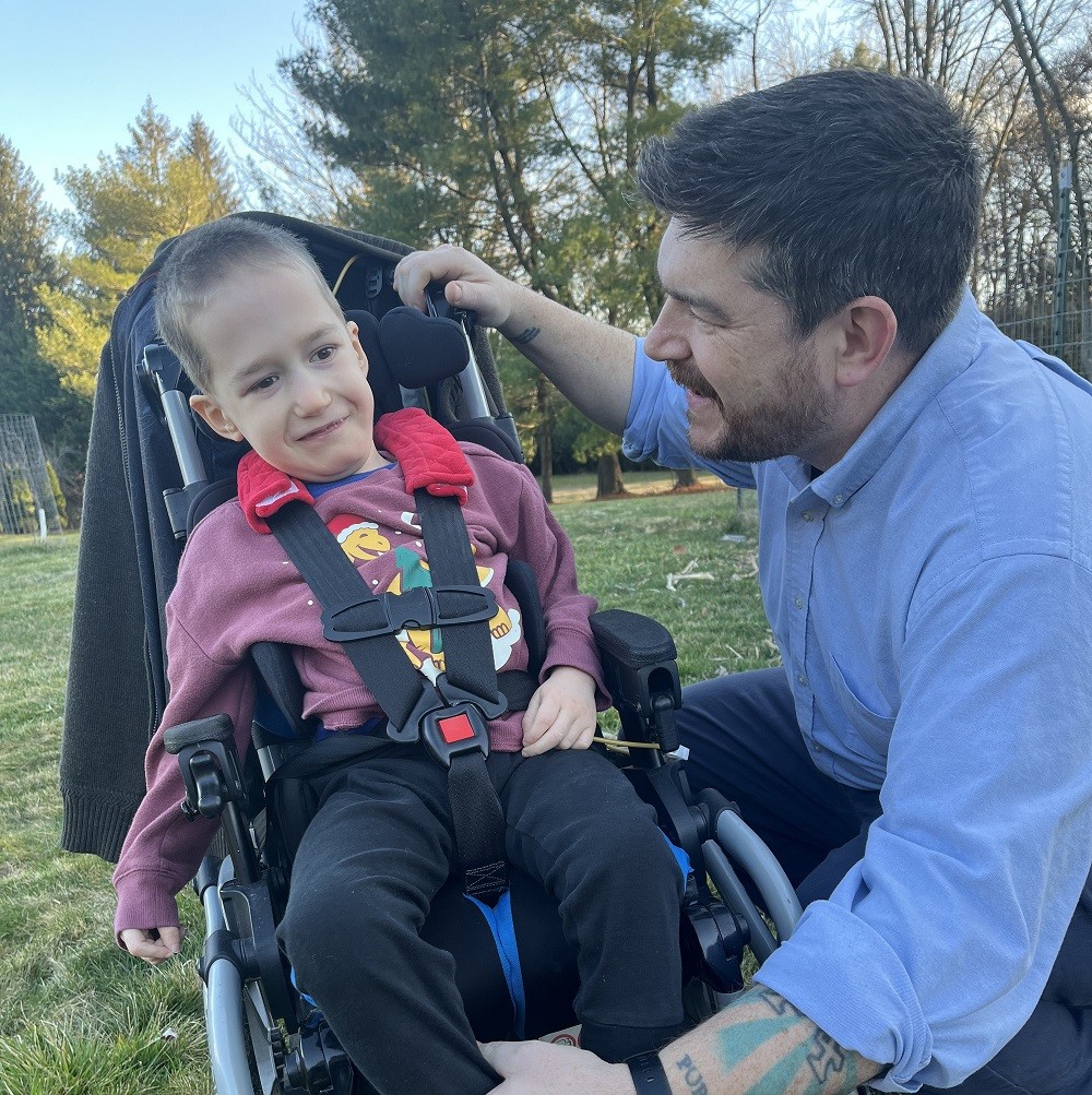6-year-old Sylvan DeSocio is seated in a therapeutic stroller with his dad outside.