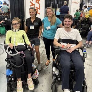Help Hope Live clients Rebecca Koltun and Lucas Towers seated in their power chairs with their parents and Kelly L Green at Abilities Expo NY Metro 2025.
