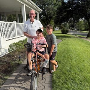 Flyers Alumni Brad Marsh with 12-year-old Tommy Shrank riding his new Flyers themed adaptive bike. July 2025.