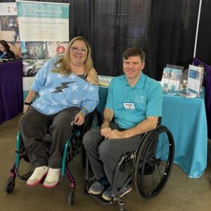 Help Hope Live client Jamie Carlson and staff member Andy Zimmer both seated in their wheelchairs at Abilities Expo Dallas 2025.