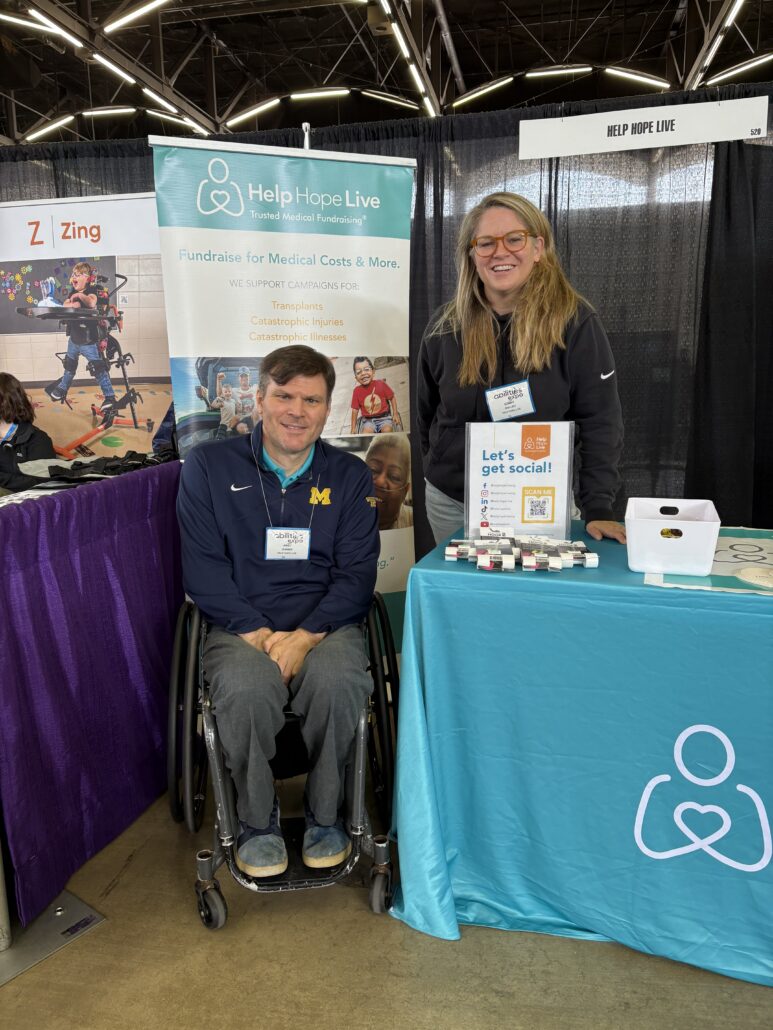 Help Hope Live's booth at Abilities Expo Dallas with Andy Zimmer, seated in his wheelchair, and Sonny Mullen, standing beside him.