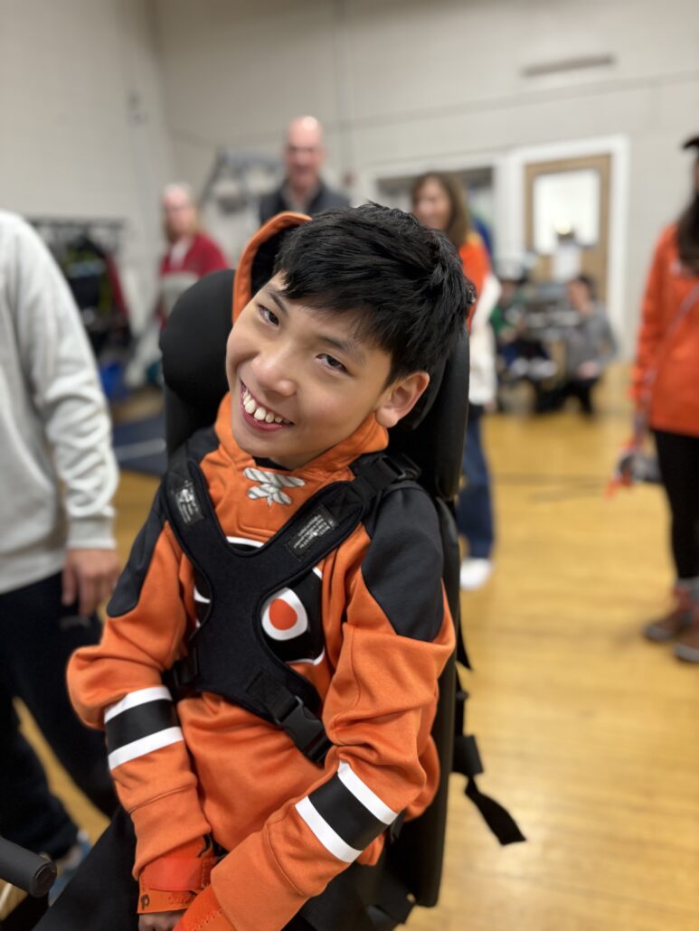 13-year-old Max Peng in Flyers orange receiving his customized adaptive bike.
