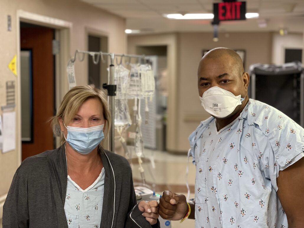 Transplant day for donor Karen Eaton and Keith Henry, both in hospital gowns and wearing masks.