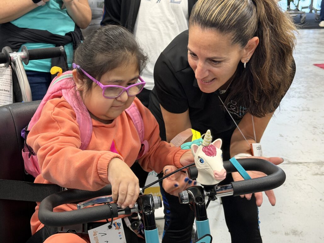 Kelly L Green watches Jeanney enjoy her new bike at Abilities Expo NY 2026.