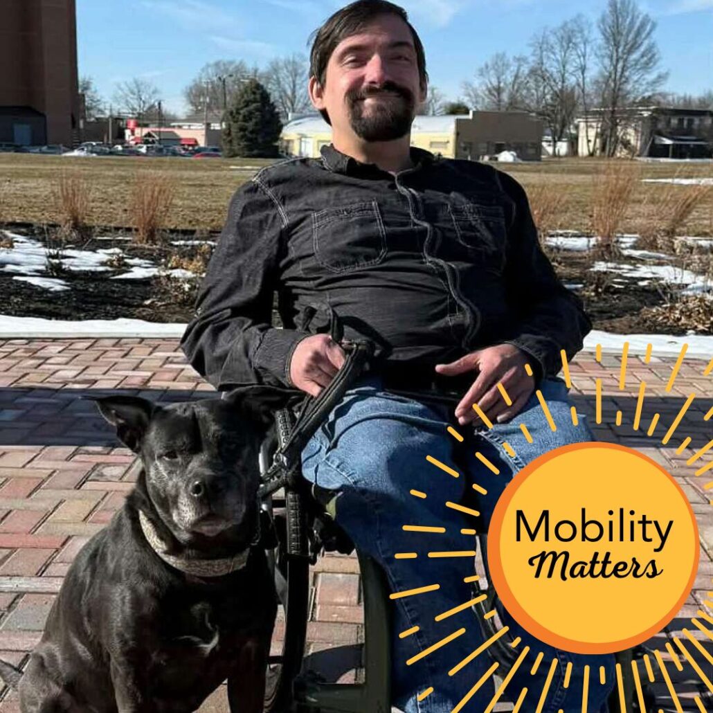 Scott Hughes seated in his manual wheelchair with his dog Karma and the text Mobility Matters.