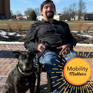 Scott Hughes seated in his manual wheelchair with his dog Karma and the text Mobility Matters.