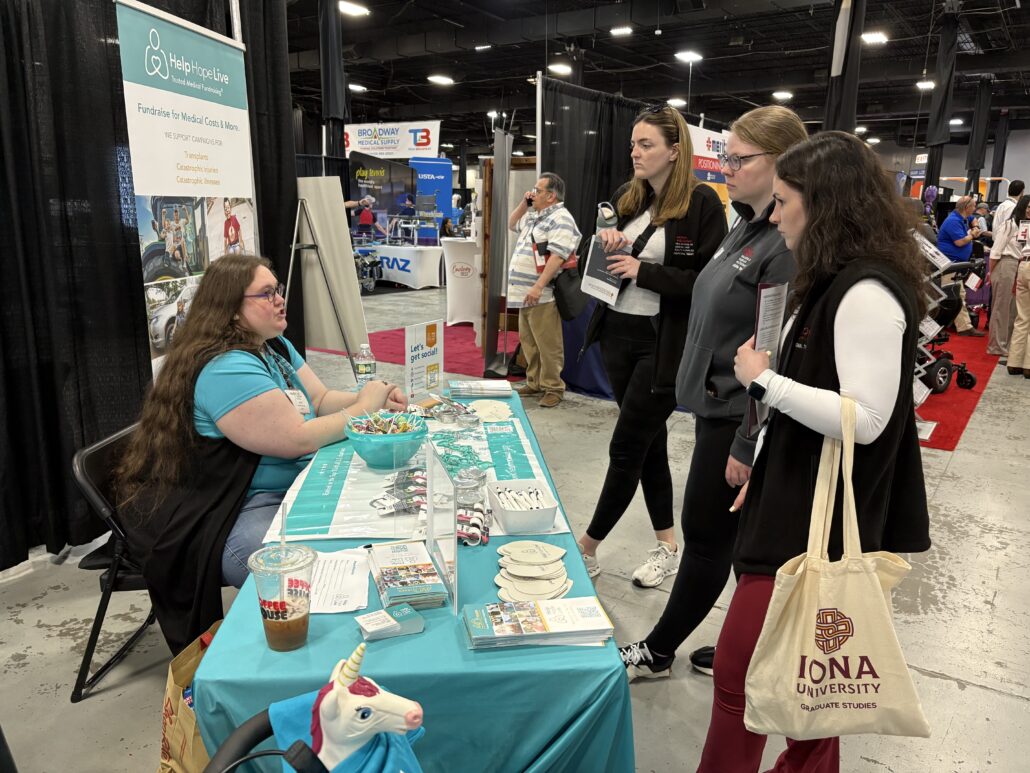 Stacia speaks to three visitors at the Help Hope Live booth at Abilities Expo NY 2026.