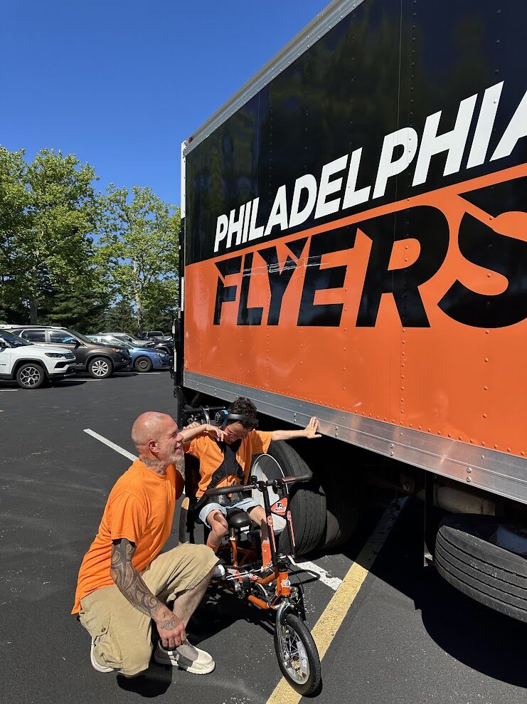 Angelo Murphy rides his new adaptive bike and reaches out to touch the Philadelphia Flyers truck at the 2026 Charity Classic.